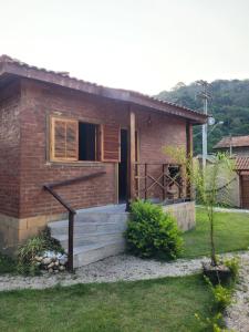 a small brick house with a staircase in a yard at Chalés das cerejeiras in Santo Antônio do Pinhal