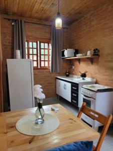 a kitchen with a table and a white refrigerator at Chalés das cerejeiras in Santo Antônio do Pinhal