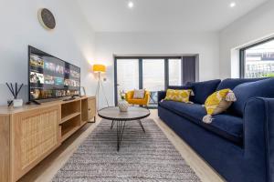 a living room with a blue couch and a tv at Sercasa - Kingston upon Thames in Kingston upon Thames