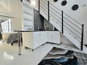 a kitchen with white cabinets and a staircase at Aqua Breeze in Cape Town