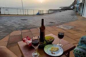 a bottle of wine sitting on a table with two glasses at Casa cueva primera línea de playa en Sardina in Gáldar