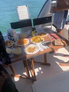 einen Tisch auf einem Boot mit Teller mit Essen drauf. in der Unterkunft Barco apartamento in El Portil