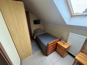 a small attic bedroom with a bed and a window at Pod Parkanami in Spiczyn +7 photos