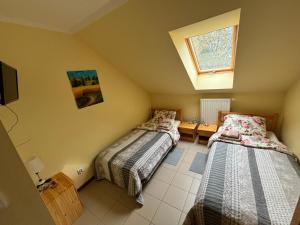 two beds in a small room with a window at Pod Parkanami in Spiczyn