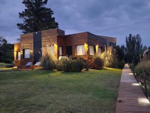 a wooden house with a lawn in front of it at Casa Cortés Golf - Exclusivo Adultos - Solo con Reserva y Aceptación de Reglamento in Sierra de la Ventana