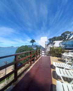 a balcony with white chairs and a view of the ocean at Apartamento Ubatuba Vista para o Mar in Ubatuba