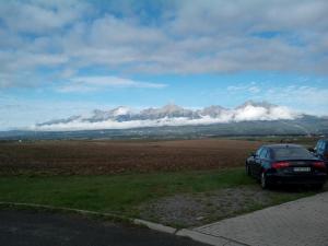 a car parked on the side of a road with mountains at Hotel Premiér Poprad 13 Jeseň vo Vysokých Tatrách in Poprad