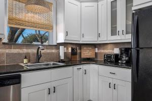 Una cocina con gabinetes blancos y un refrigerador negro. en Haus on the Hill - Hot Tub & 1 Mile From Main St, en Fredericksburg