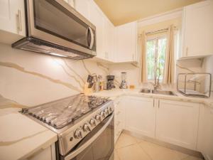 ソスアにあるGarden Condos 21, Modern 1BR APT In Sosua Strip GUEST FRIENDLYのコンロとシンクのある白いキッチン