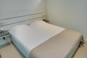 a bedroom with a bed with white sheets at De Zeedistel in Oostkapelle