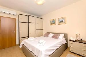 a bedroom with a bed with white sheets and a dresser at Apartments Maris in Tribunj
