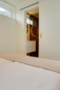 a white bed in a room with a mirror at De Zeedistel in Oostkapelle