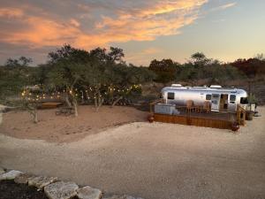 an rv parked in a field with a sunset at Airstream Getaway - Hot Tub & Fire Pit in Luckenbach