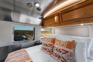 a bedroom with a bed and a window in an rv at Airstream Getaway - Hot Tub & Fire Pit in Luckenbach