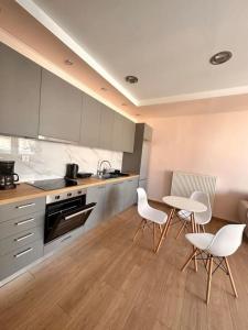 Una cocina con sillas blancas, una mesa y armarios. en The rabbits' house, en Nauplia