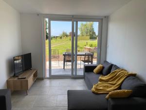 a living room with a couch and a tv at Un séjour à la ferme in Sommery