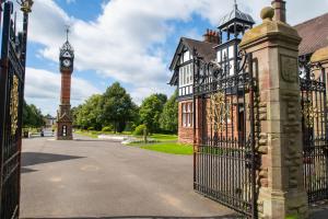 a gate to a building with a clock tower at 4BR Cheshire East/Townhouse/Central - Close to Bentley in Crewe