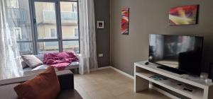 un soggiorno con divano, TV e finestra di PACEVILLE St Julians Apartments a San Giuliano