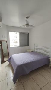 a bedroom with a bed with a purple bedspread and a window at Amplo apartamento próximo ao Mar-Mar Grosso-Laguna in Laguna