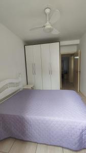 a bedroom with a purple bed and white cabinets at Amplo apartamento próximo ao Mar-Mar Grosso-Laguna in Laguna