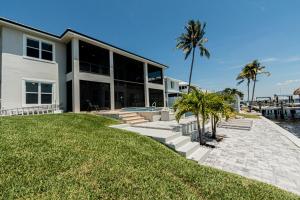 une grande maison avec des palmiers devant dans l'établissement Breathtaking 6BD Riverfront Mansion w Pool, à Cape Coral