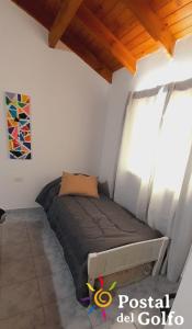 a small bed in a room with a window at Postal del Golfo in Las Grutas