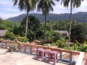 two pink chairs sitting on a deck with palm trees at Lanta Orange House in Ko Lanta