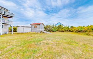 a large yard with a white building and a house at Waves of Lunasea 568 in Rodanthe