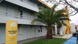 een palmboom voor een gebouw bij Premiere Classe Bordeaux Eysines in Eysines