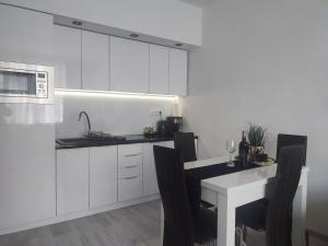 a kitchen with white cabinets and a table with chairs at Apartament LUX w centrum Konina in Konin +4 photos