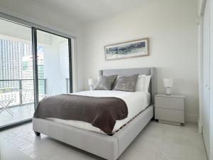 a white bedroom with a bed and a large window at Private Terrace in Luxury 3BR Condo in Brickell in Miami