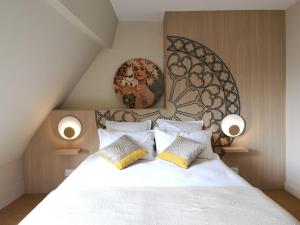 a bedroom with a large white bed with pillows at Les visages des Tournelles in Reims +9 photos