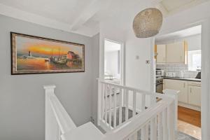 a white staircase in a home with a painting on the wall at Lovely Home In Bletchley Milton Keynes in Bletchley +23 photos