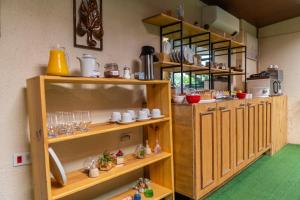 a kitchen with wooden shelves with cups and dishes at Refúgio da Enseada - Suítes in Ubatuba