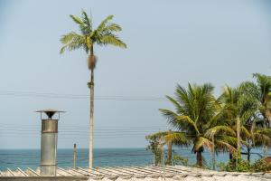 a palm tree on a beach with the ocean at Refúgio da Enseada - Suítes in Ubatuba