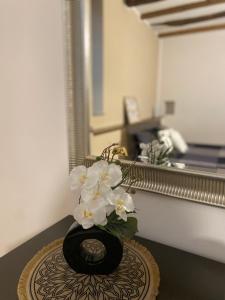 a black vase with white flowers on a table at Lacasadeitati in Lecco
