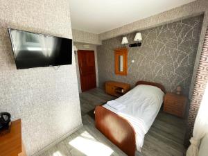 a bedroom with a bed and a flat screen tv at Pensjonat Stary Browar in Szubin