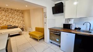 a kitchen with a sink and a couch in a room at Studio cosy et lumineux proche Paris et Stade de France in Stains