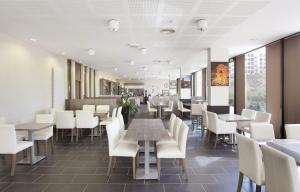 a dining room with tables and white chairs at Studio Harmonie Confluence Lyon City et piscine chauffante in Lyon