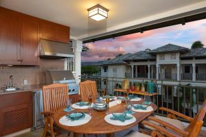 a wooden table on a balcony with a kitchen at Hilton Pool Pass Included, Kolea - Luxe Penthouse, Walk to Beach in Waikoloa