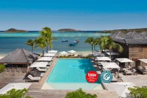 古斯塔维亚Le Barthélemy Hotel & Spa的一个带遮阳伞和海滩的度假游泳池