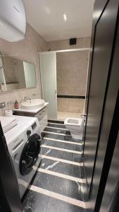 a bathroom with a washer and a sink and a toilet at Skanderbeg Apartment in Tirana
