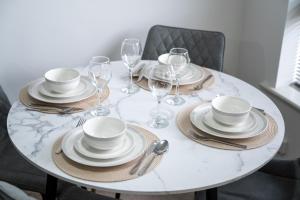 a white table with plates and wine glasses on it at Superb Two Bedroom House Near Etihad & Coop Live - Free Parking in Manchester