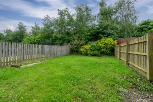 a wooden fence in a yard with a green lawn at Superb Two Bedroom House Near Etihad & Coop Live - Free Parking in Manchester