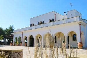 un edificio bianco con archi e piante in primo piano di Agriturismo Puntarelle a San Donato di Lecce