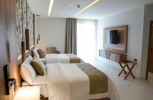 a hotel room with two beds and a television at Nöa Hotel in Piñas
