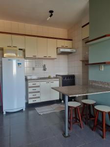 a kitchen with a refrigerator and a table and stools at Residencial Thermas Rio Caldas 801 in Caldas Novas