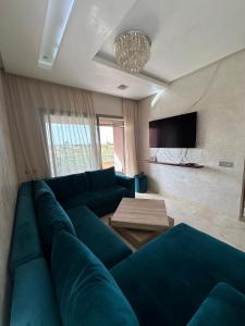 Una sala de estar con un sofá azul y una mesa. en Sublime Studio Prestigia Agate, en Marrakech