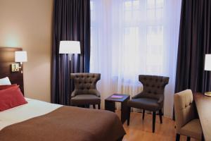 a hotel room with a bed and two chairs and a window at Home Hotel Drott in Karlstad