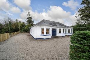 a small white house in a gravel yard at Portsalon Cottage in Portsalon